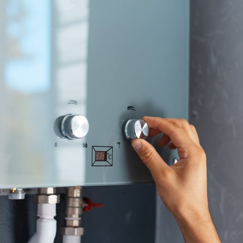 close-up-male-hand-adjusting-temperature-water-heater-modern-home-gas-fired-boiler close-up-male-hand-adjusting-temperature-water-heater-modern-home-gas-fired-boiler